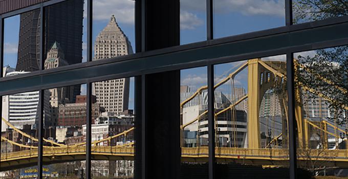 Pittsburgh buildings and bridge reflected in window